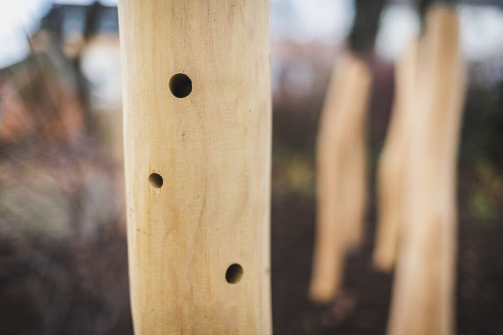 Detail opracovaného akátového kůlu s otvory pro hmyzí hotel na školním hřišti.